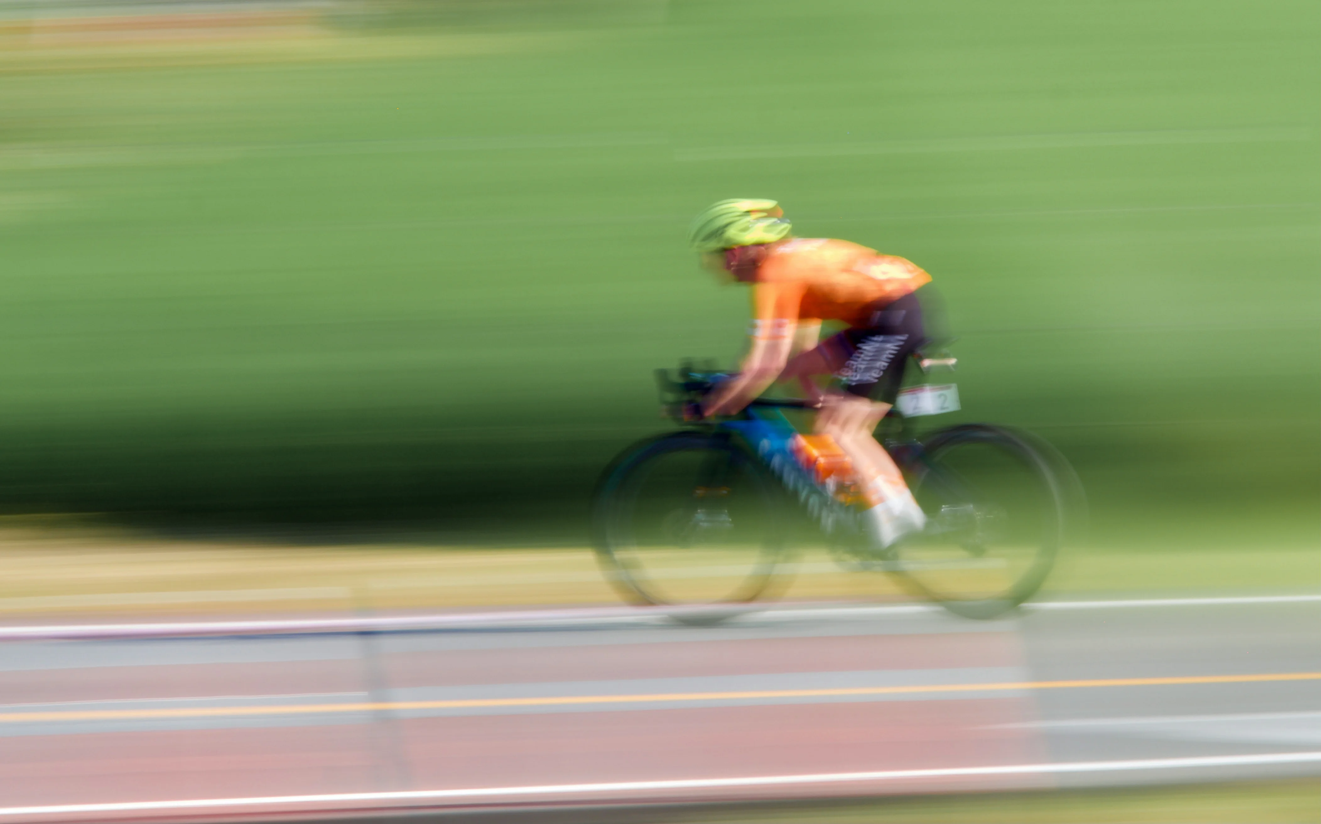 Cyclist in an orange jersey riding at speed, captured with motion blur